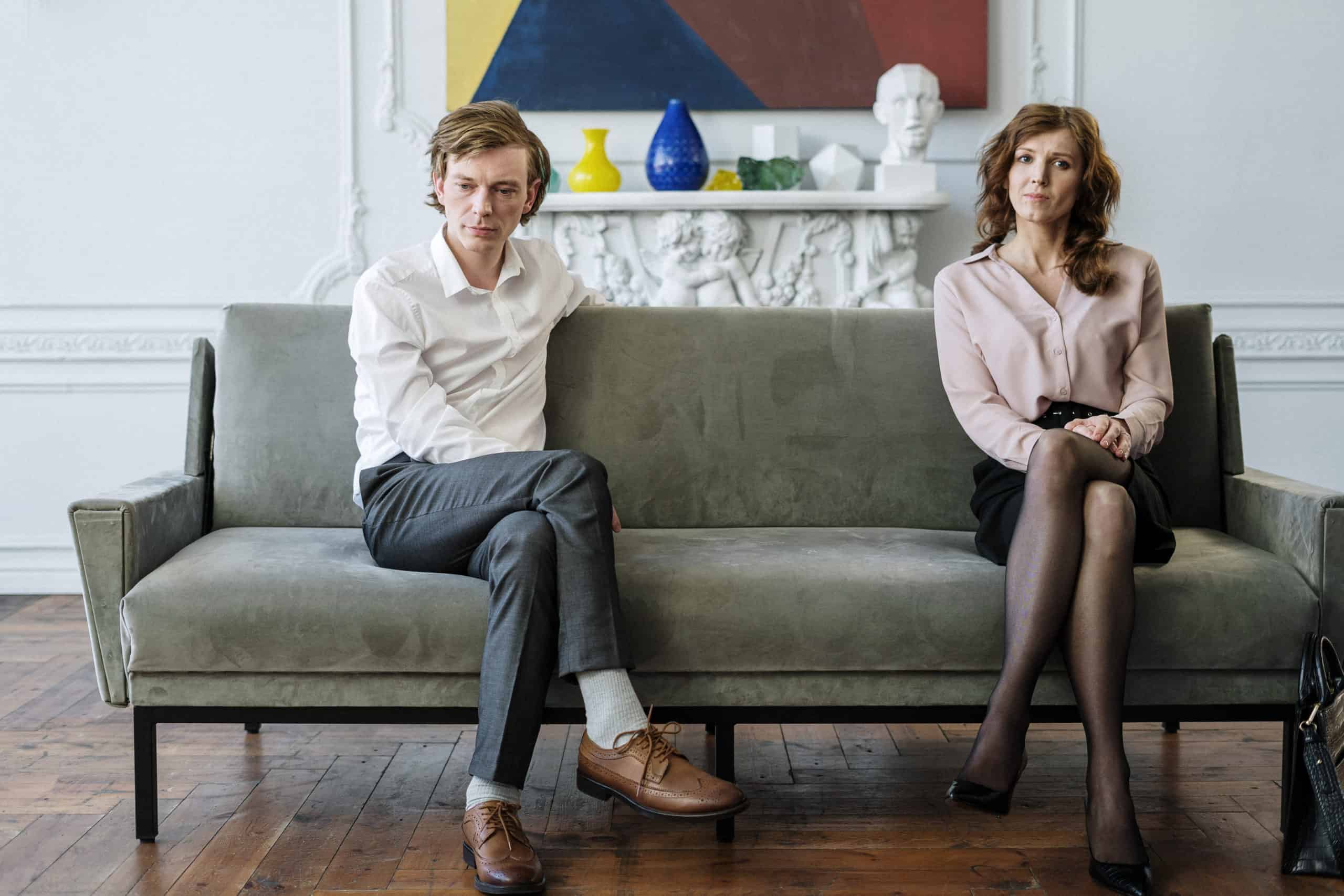 Woman in white dress shirt and black pants sitting on gray couch