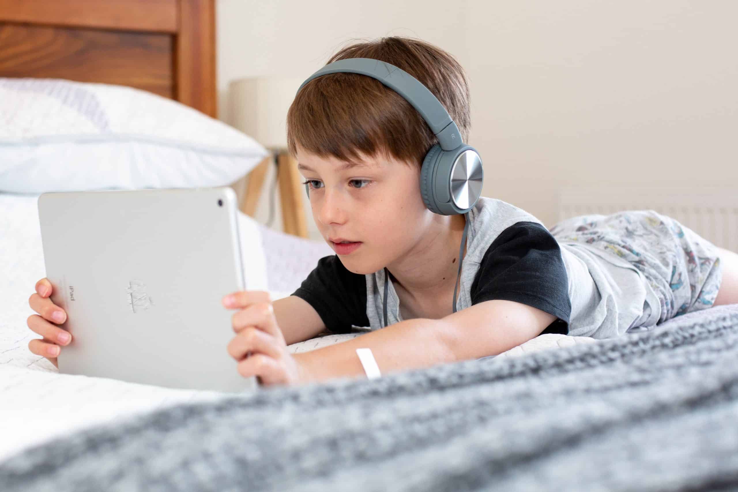 Boy using iPad with headphones on