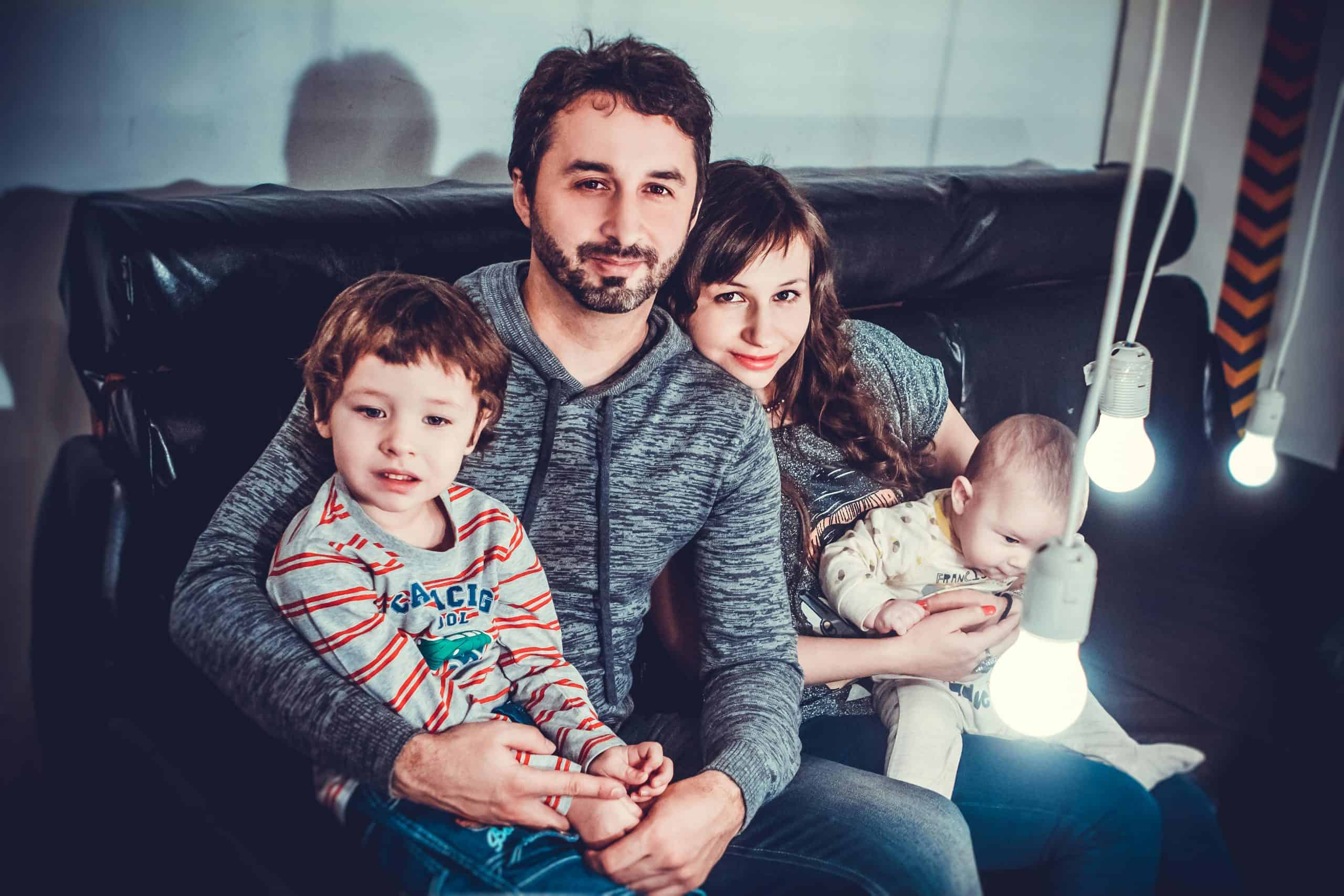 Man and woman carrying babies while sitting on chair