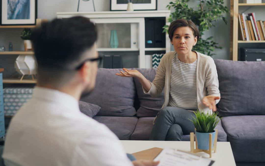 a woman sitting on a couch talking to a man